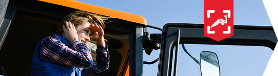 Jeune agricultrice les cheveux au vent à la porte de son tracteur.